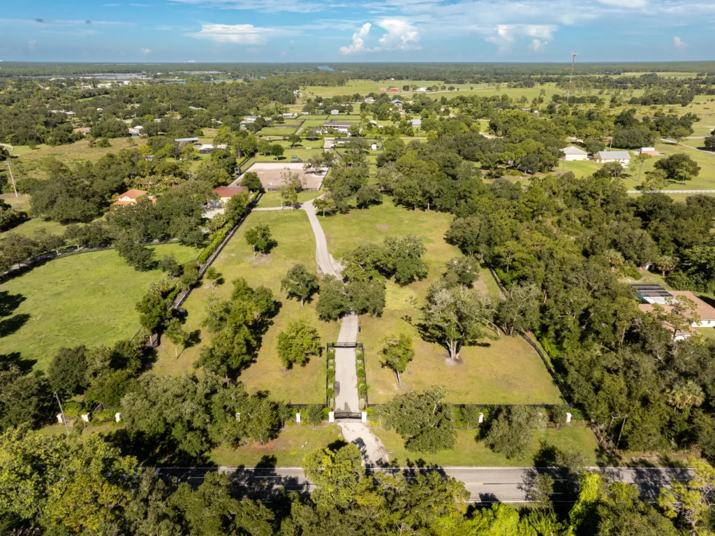 Aerial view of the gated entrance, acreage, and grounds at 21571 N River Rd in Alva, Florida